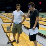 Desly makes a phone call while Dan looks on... holding a very large hammer